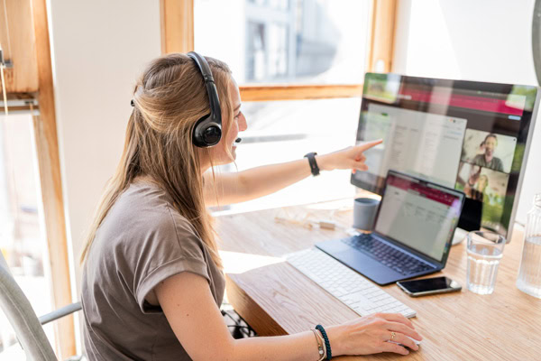 vrouw met koptelefoon wijst naar computerscherm