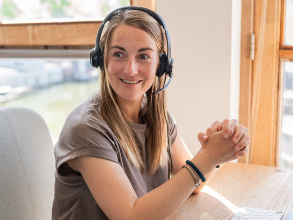 Vrouwelijke klantenservice medewerker met headset die vriendelijk en professioneel klanten ondersteunt via een callcenter.