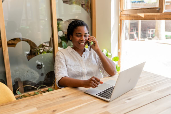 vrouw lachend aan het bellen achter haar laptop
